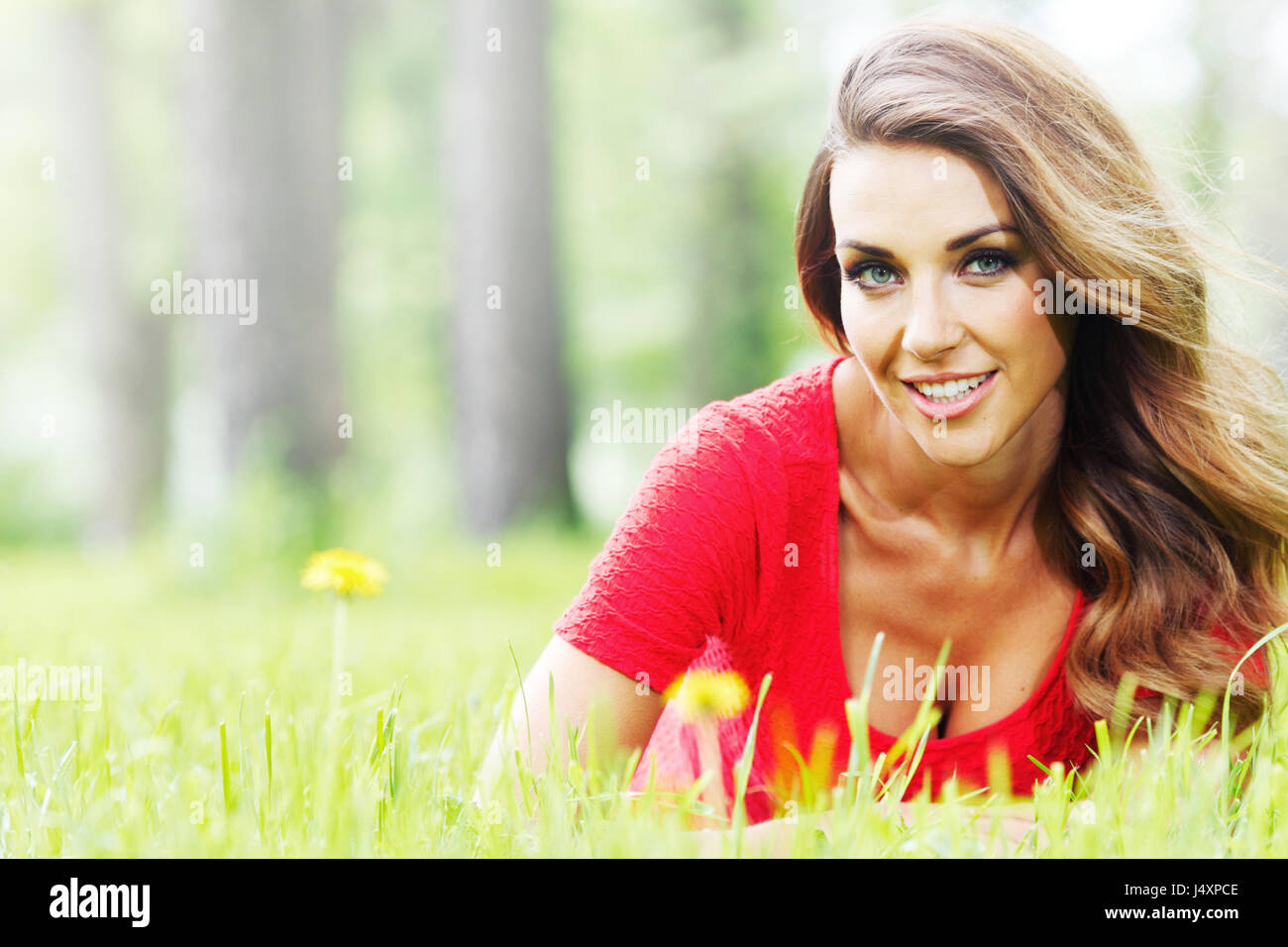 Beautiful young woman in red dress lying on grass Stock Photo - Alamy