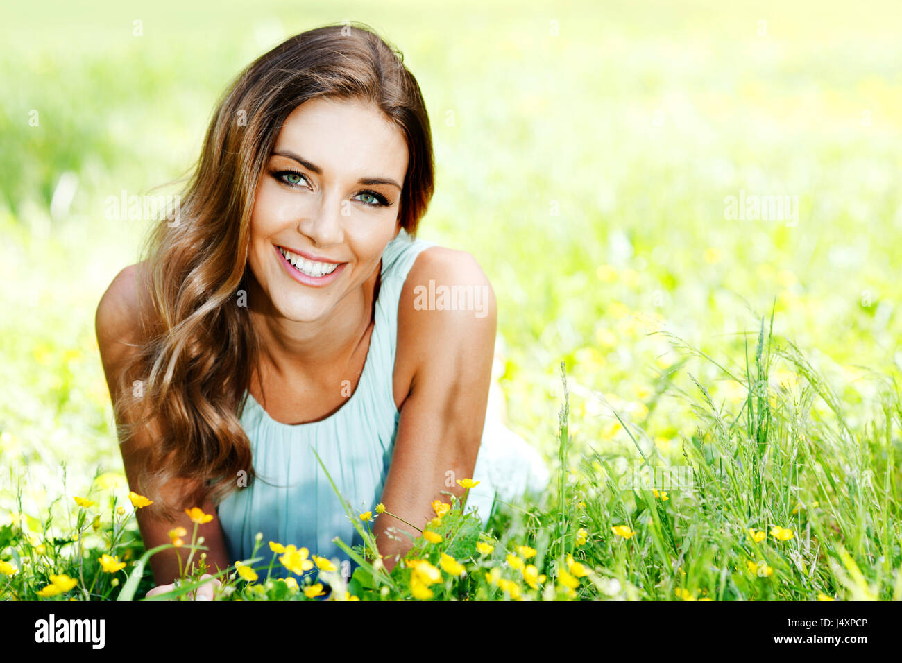 Beautiful young woman in blue dress lying on grass Stock Photo - Alamy