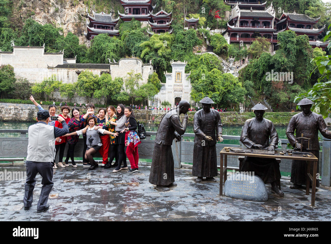 Zhenyuan, Guizhou, China.  Chinese Tourists Posing for Photo next to Sculpture Depicting Imperial Customs Agents. Stock Photo
