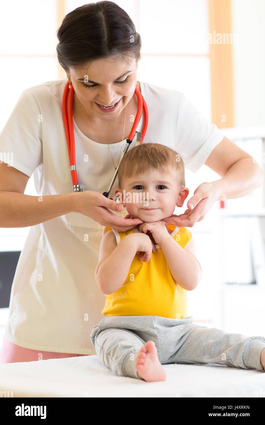 Pediatrician doctor touching the throat of kid patient in the office Stock Photo