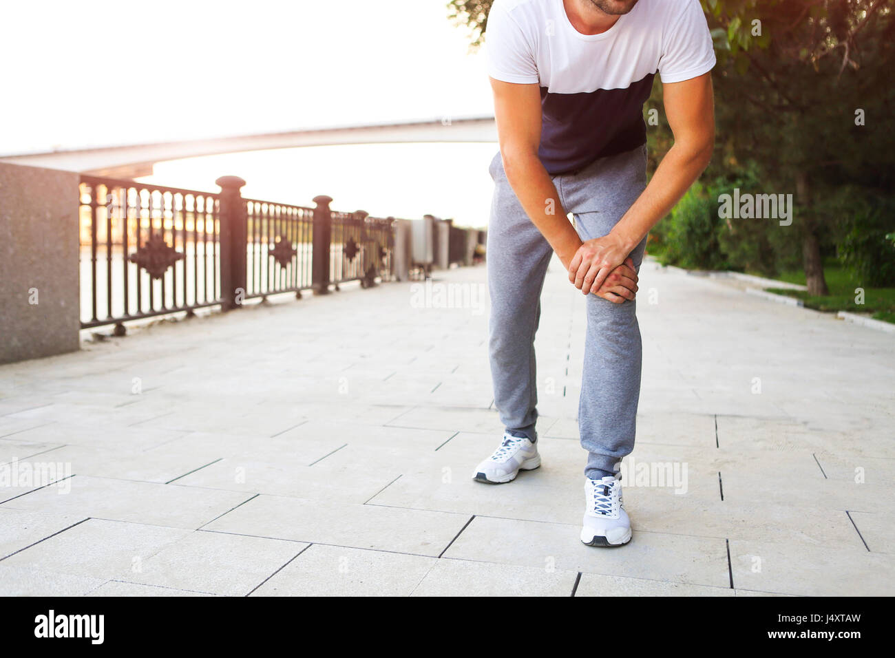 Running injury. Man out jogging with knee pain in park Stock Photo Alamy