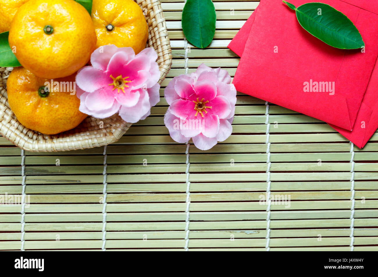 Top view  accessories Chinese new year festival decorations.orange,leaf,wood basket,red packet,plum blossom on bamboo background with copy space. Stock Photo