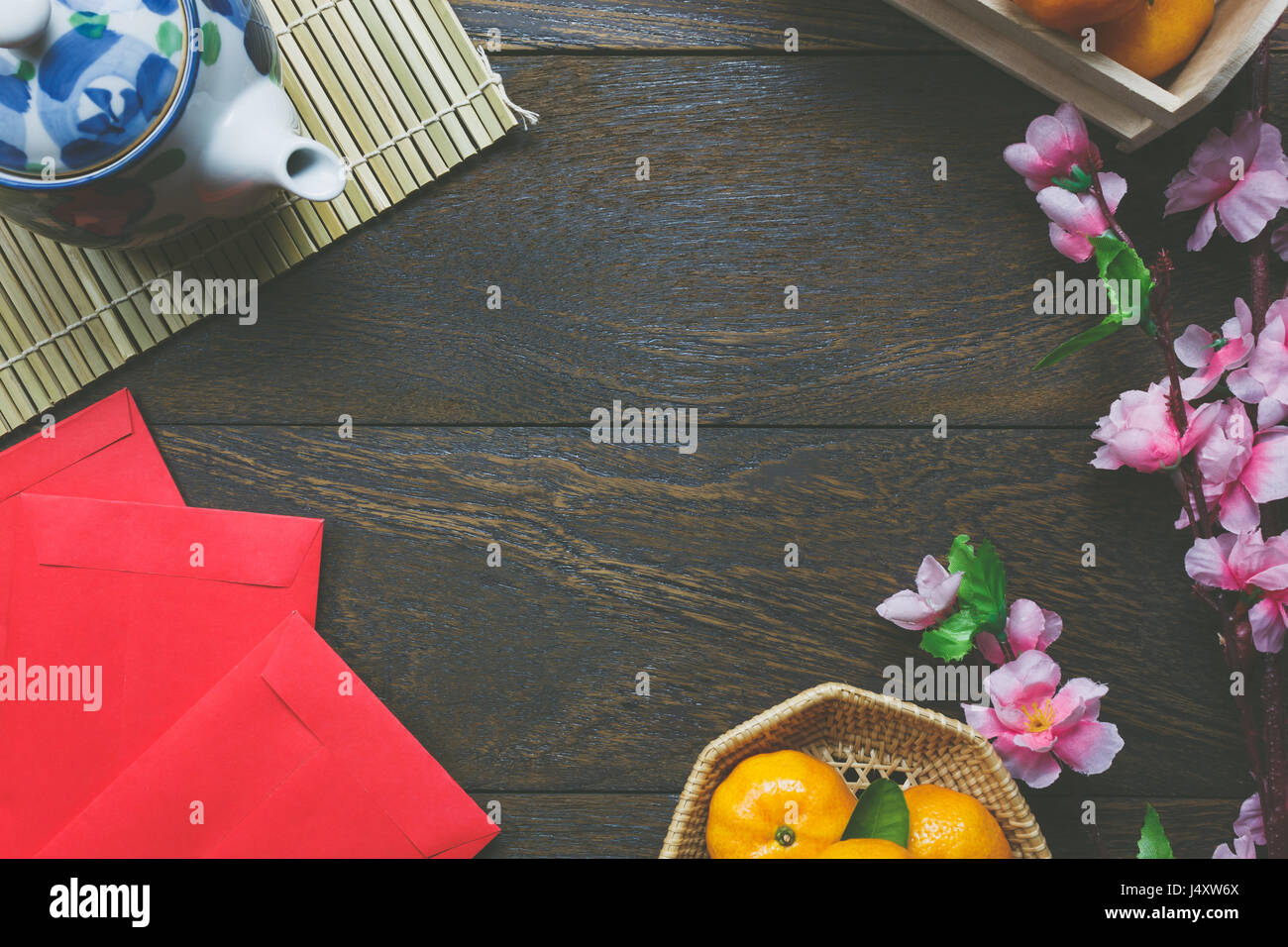 Top view accessories Chinese new year festival decorations.orange,leaf,wood basket,red packet,plum blossom,teapot on wooden table background. Stock Photo