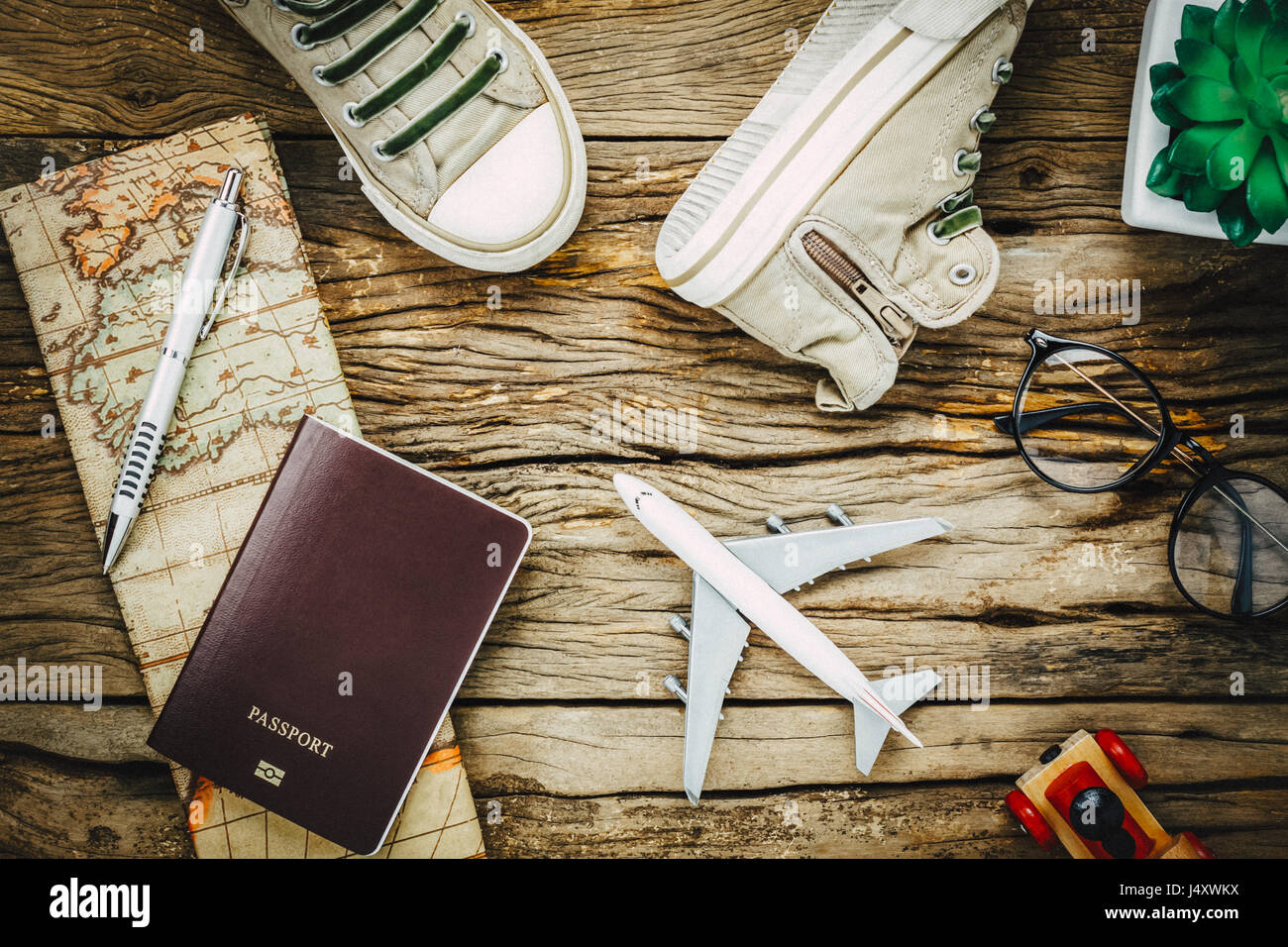 Top view essential travel items.The shoes notebook tree map passport airplane car eyeglasses on rustic  wooden background. Stock Photo