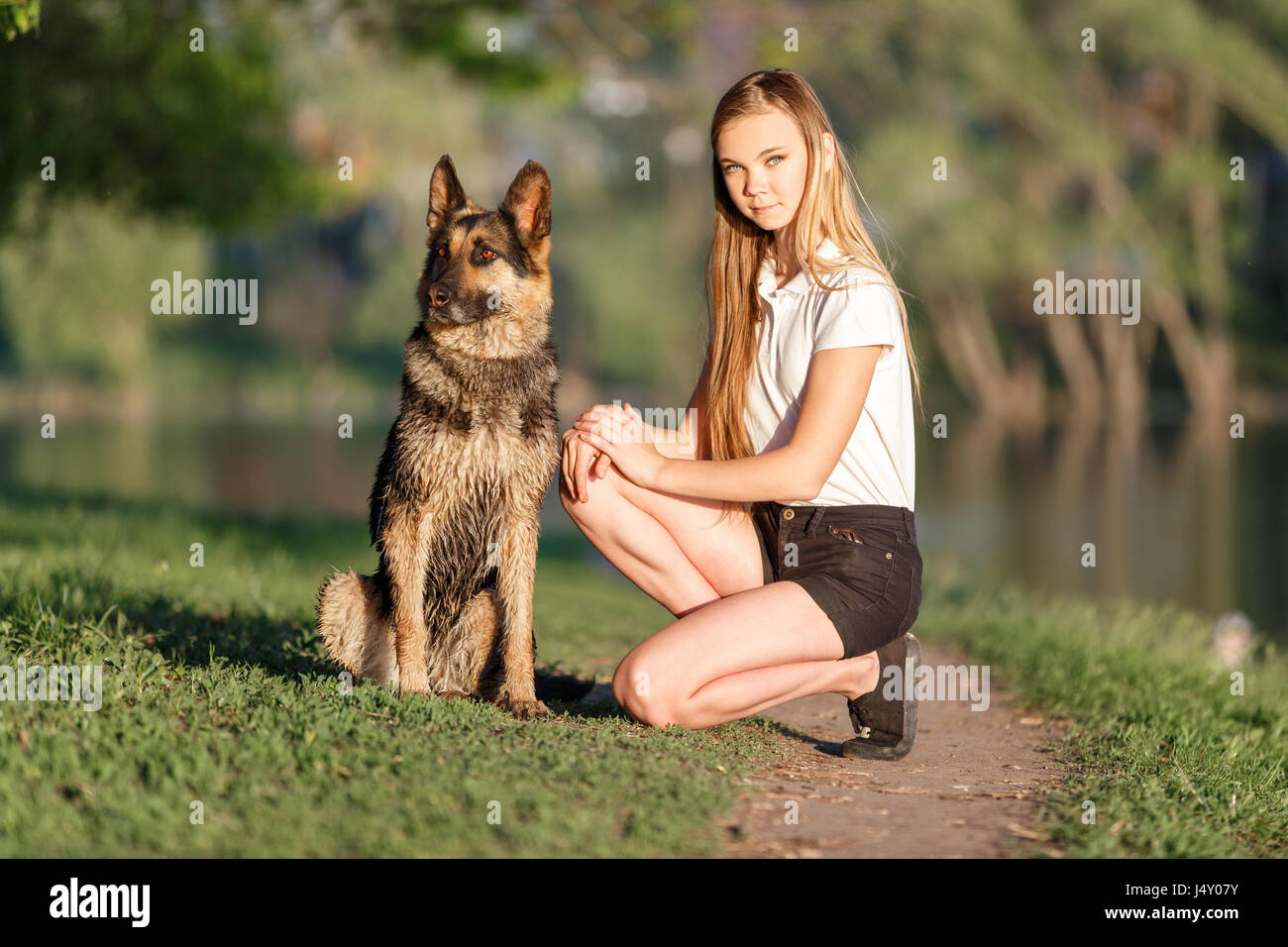 Teenage girl in white shirt with her german shepherd sitting on pathway ...
