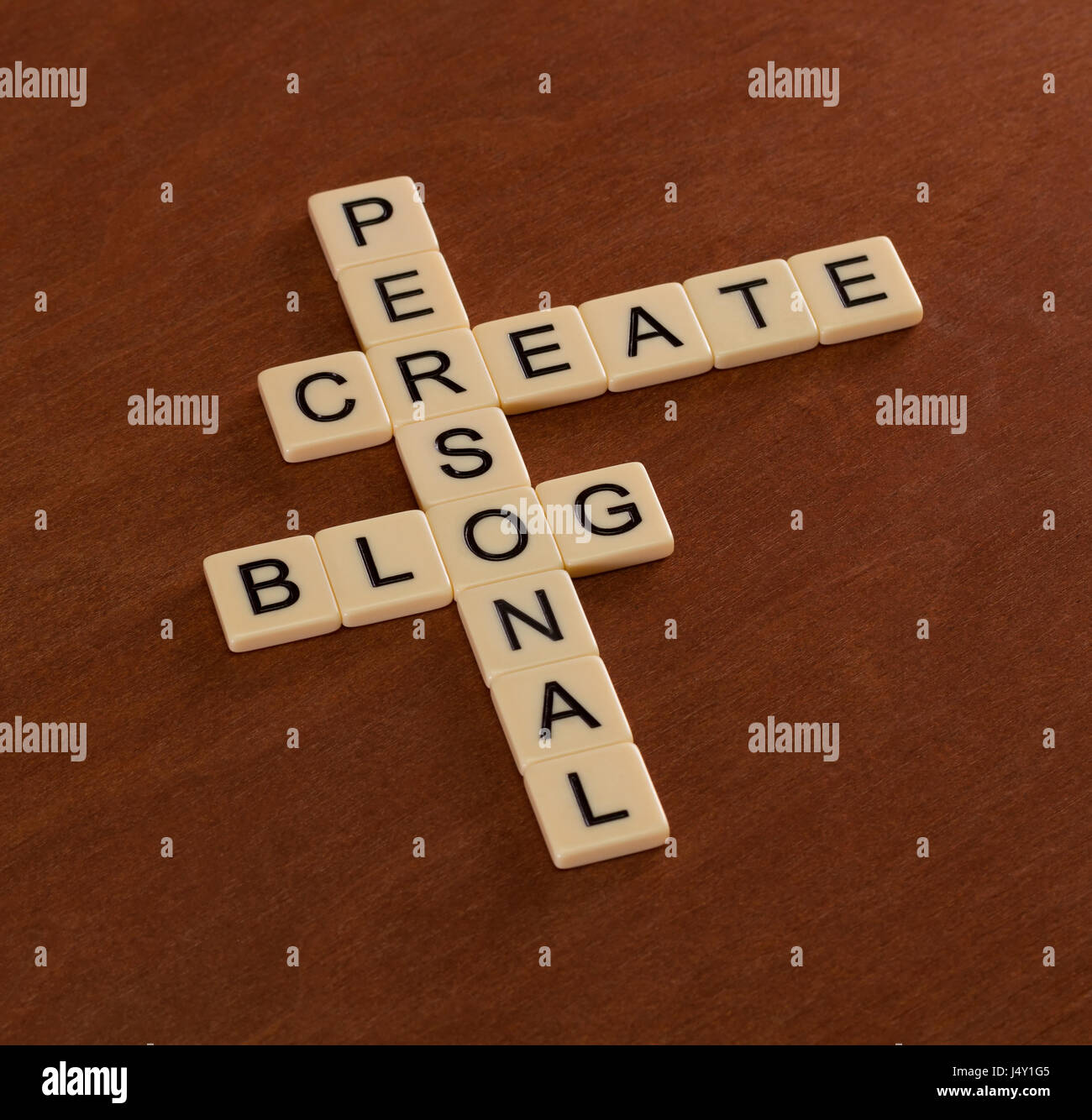 Crossword puzzle with words Create Personal Blog. Social networking concept. Ivory tiles with capital letters on mahogany board. Stock Photo