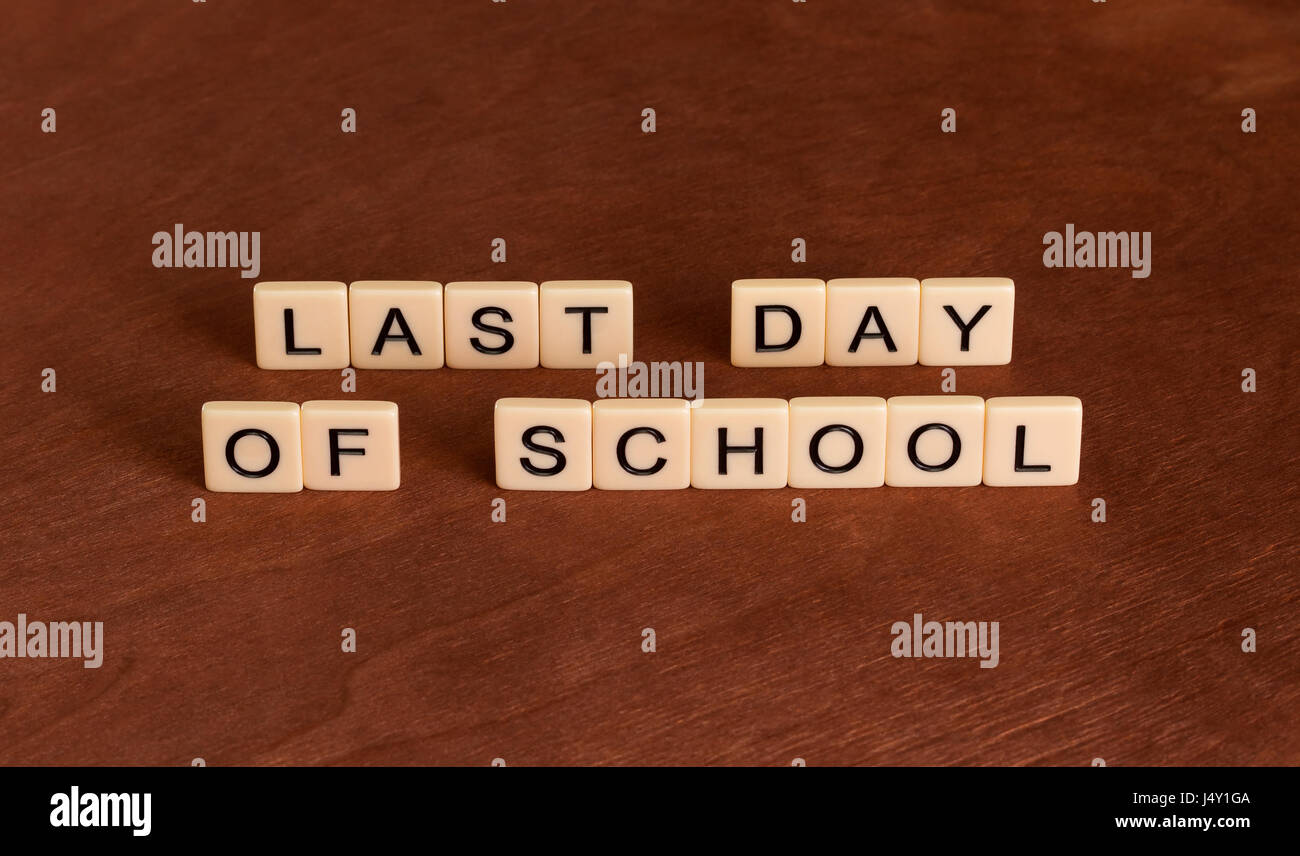 Last date of school. School's Out concept. Ivory tiles with capital letters on mahogany board. Stock Photo