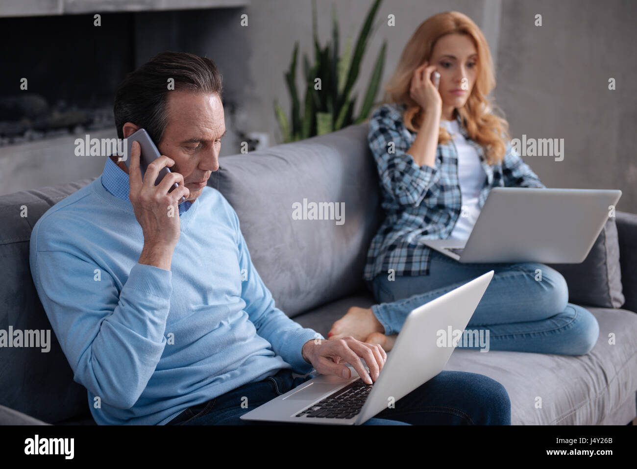 Concentrated mature couple using gadgets at home Stock Photo