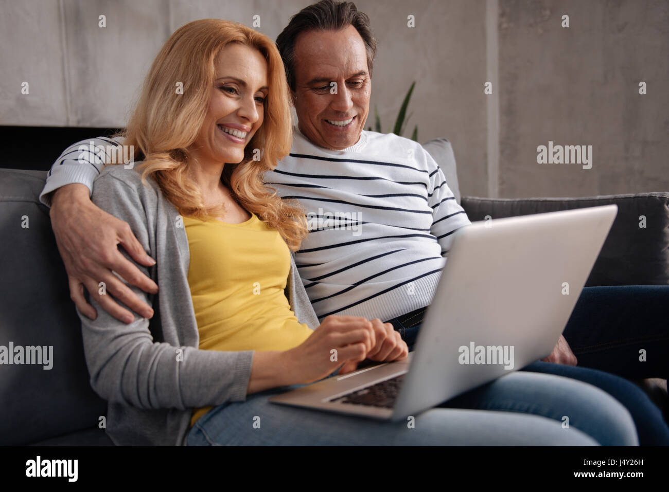 Delighted mature couple enjoying new electronic gadget at home Stock Photo