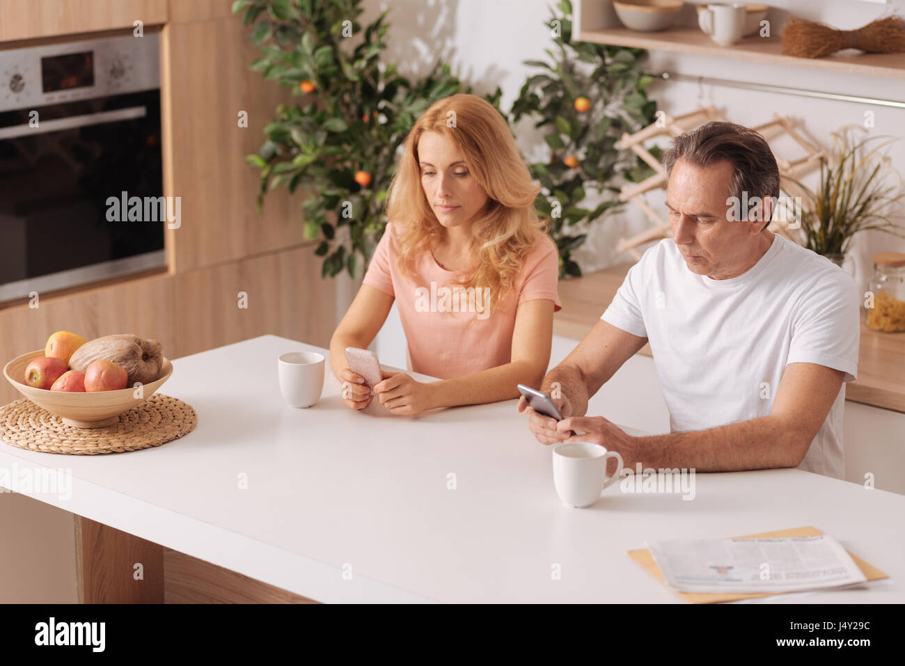 Apathetic mature couple starring at smartphones at home Stock Photo