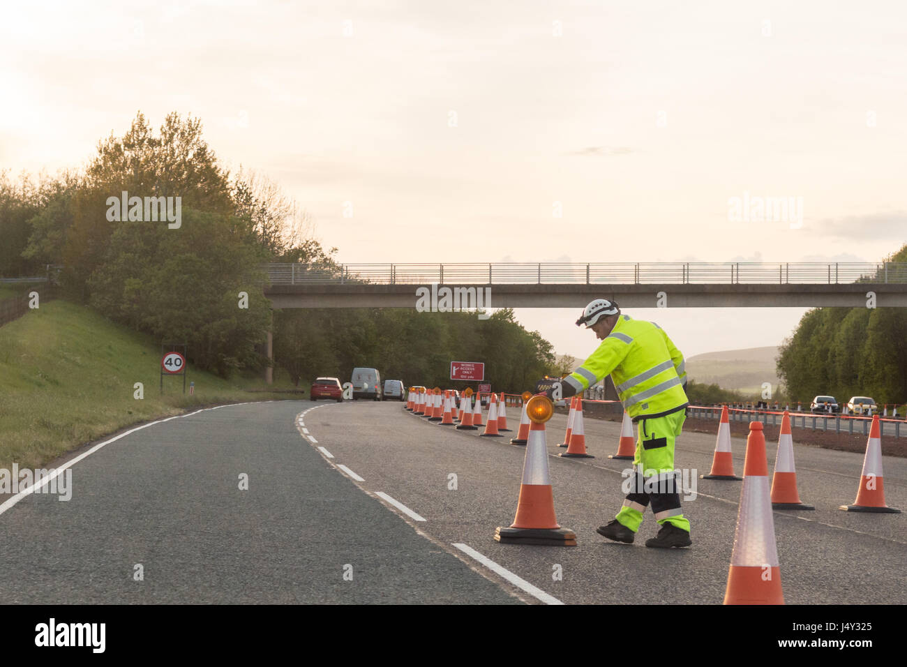 Road worker close to traffic on UK motorway - 40mph speed limit for safety protection Stock Photo