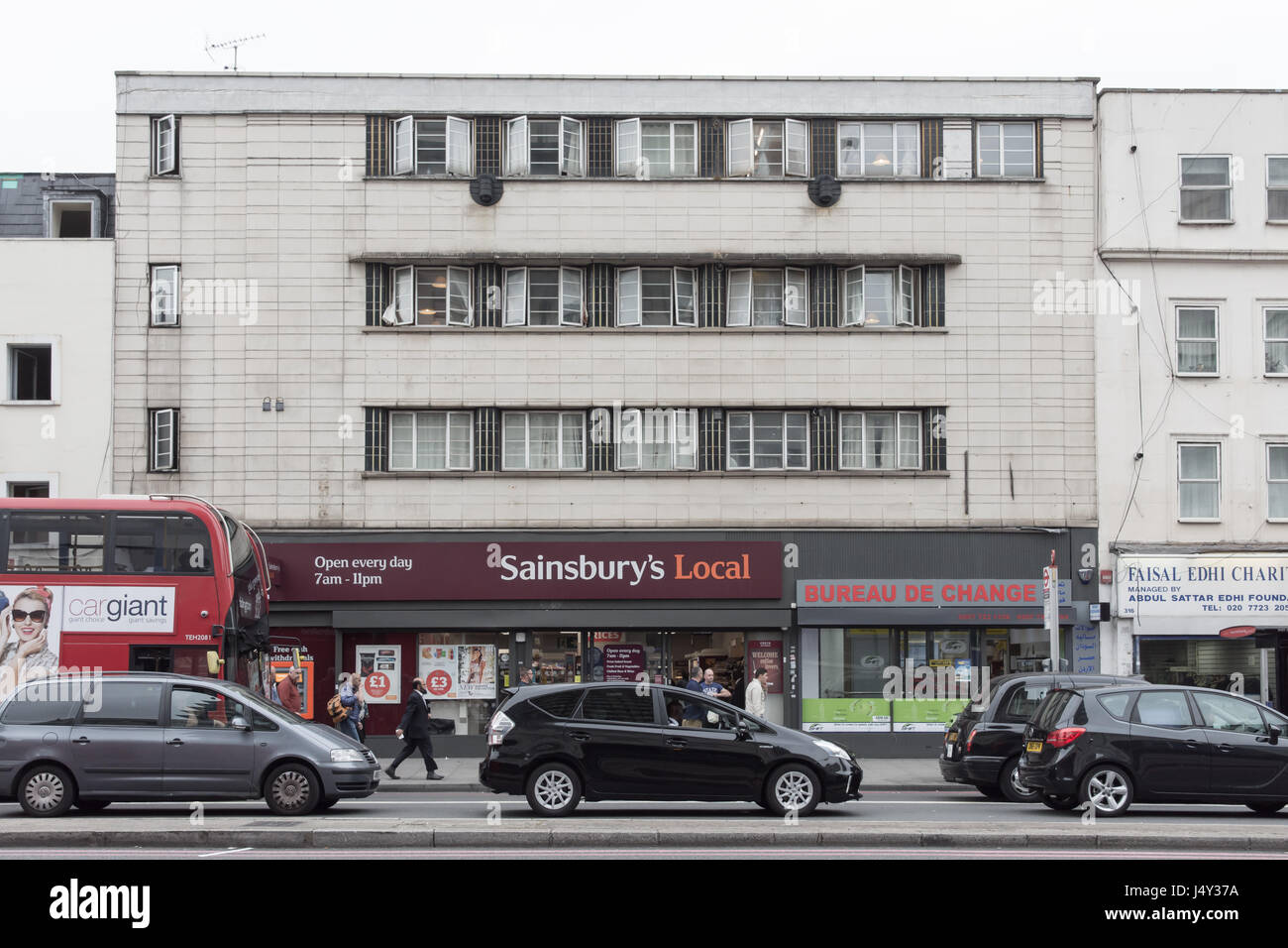 London, England - July 15, 2016: Traffic queuing on the Edgware Road beside run-down buildings and a Sainsbury's Local supermarket near Paddington in  Stock Photo