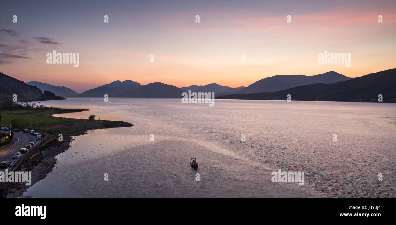 The mountains of the Ardnamurchan Peninsula are silhouetted against the sunset, seen across Loch Linnhe from the Ballachulish Bridge. Stock Photo