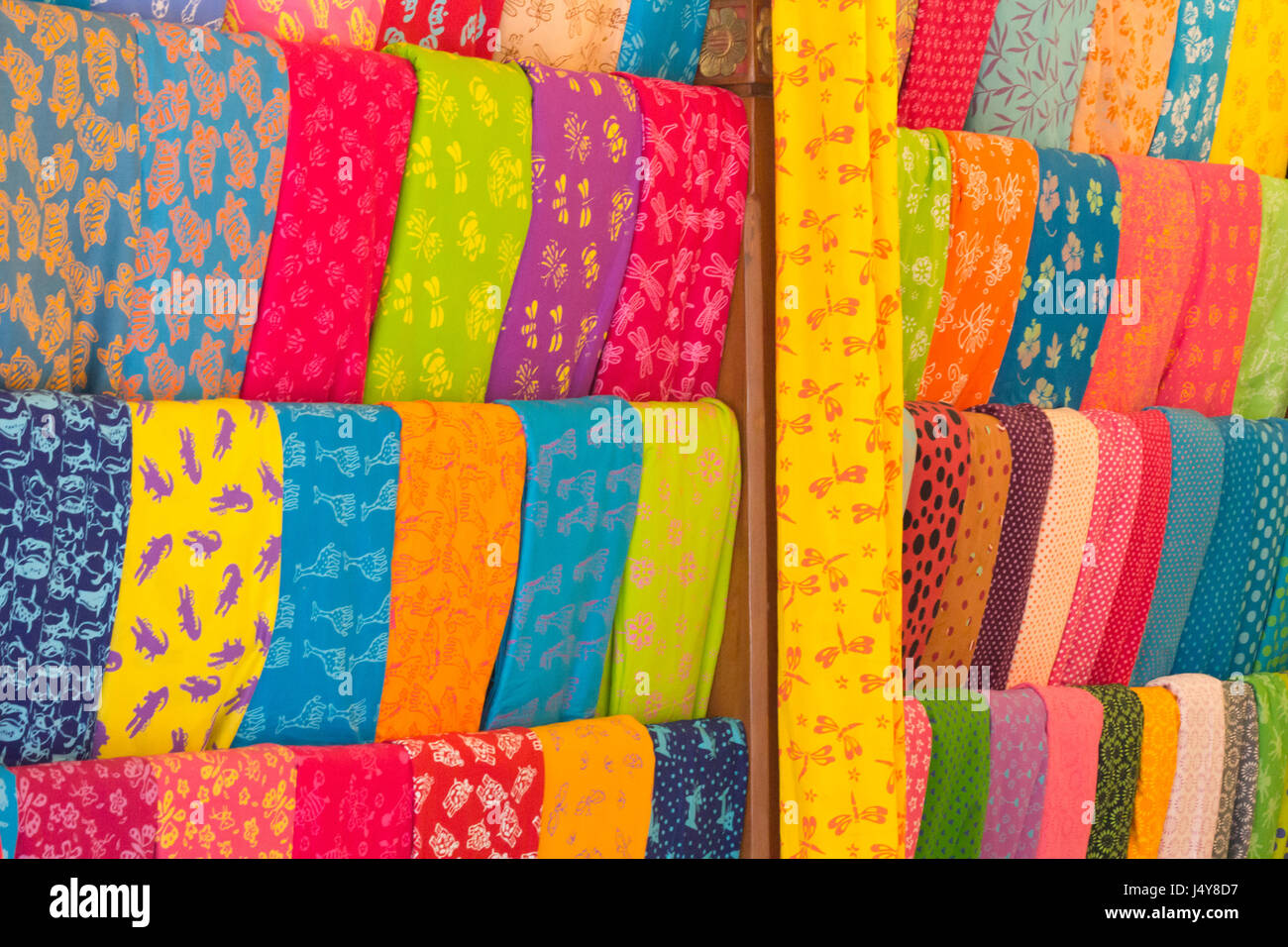 Bolts of colourful cloth hanging in a shop in Denpasar, Bali, Indonesia Stock Photo