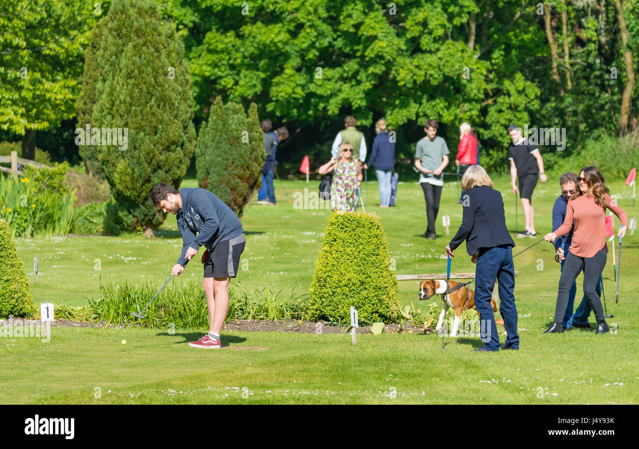 Families putting on a mini golf or putting course at Mill Road Leisure & Cafe in Arundel, West Sussex, England, UK. Stock Photo