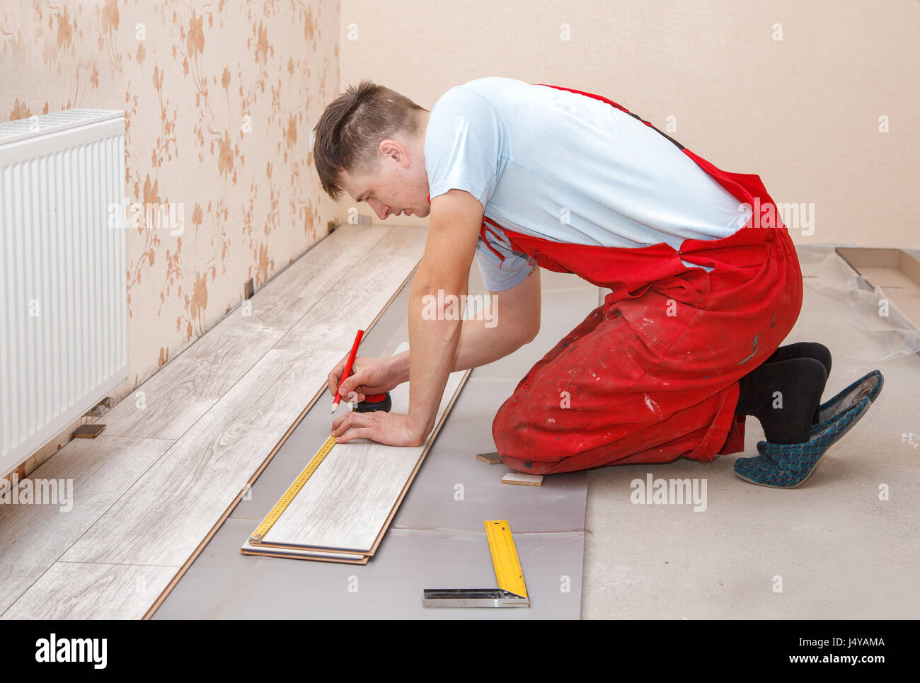young handyman installing wooden floor in new house Stock Photo Alamy