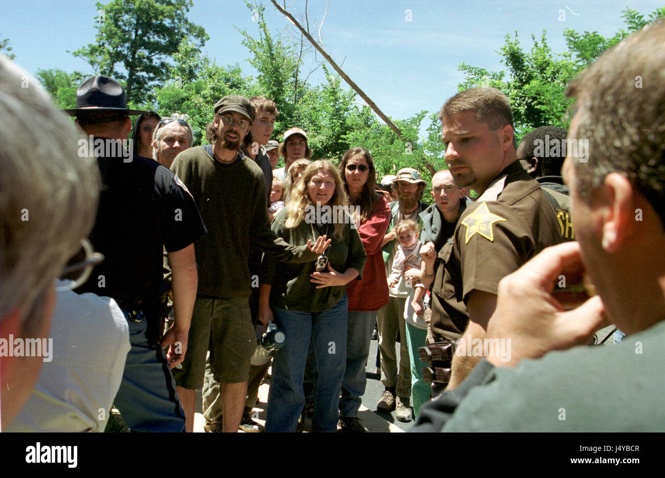 Tensions rise at  police line as treesitters are arrested July 6, 2001 in Bloomington, Indiana. To stop a low income housing division from being built on land filled with trees and sinkhole a tree sit began during March 2001 and lasted more than 100 days in Bloomington, Indiana. The first sitter Tracy 'Dolphin' McNeely secretly climbed down in in late June citing burnout after she was supported by a ground crew for months. Another sitter, Mike 'Moss' Englert, who had replaced her managed to avoid being arrested when waw enforcement authorities raided the Bluebird treesit site on July 6, 2001.  Stock Photo