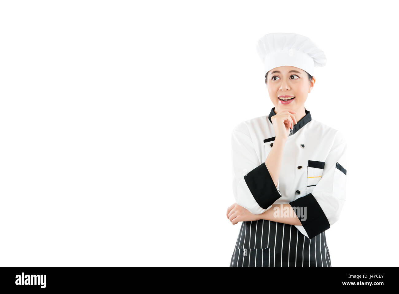 Chef thinking looking smiling and happy to the side. Woman cook or baker in chef uniform and hat. Young asian female isolated on white background. pro Stock Photo