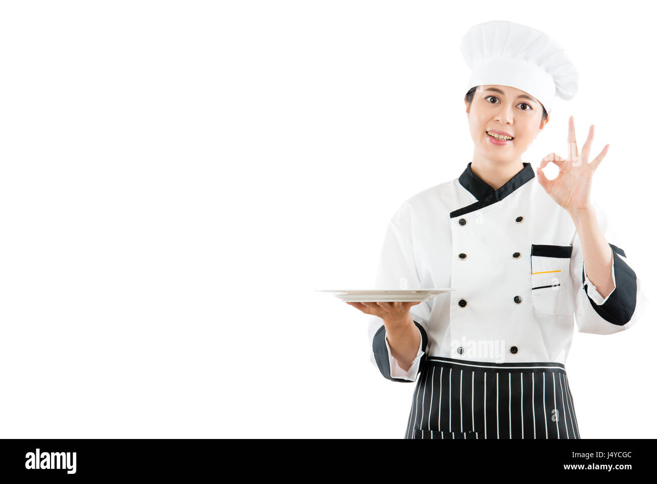 chef holding empty dish showing delicious food in the air with copyspace and showing okay gesture standing on white background taking photo for advert Stock Photo