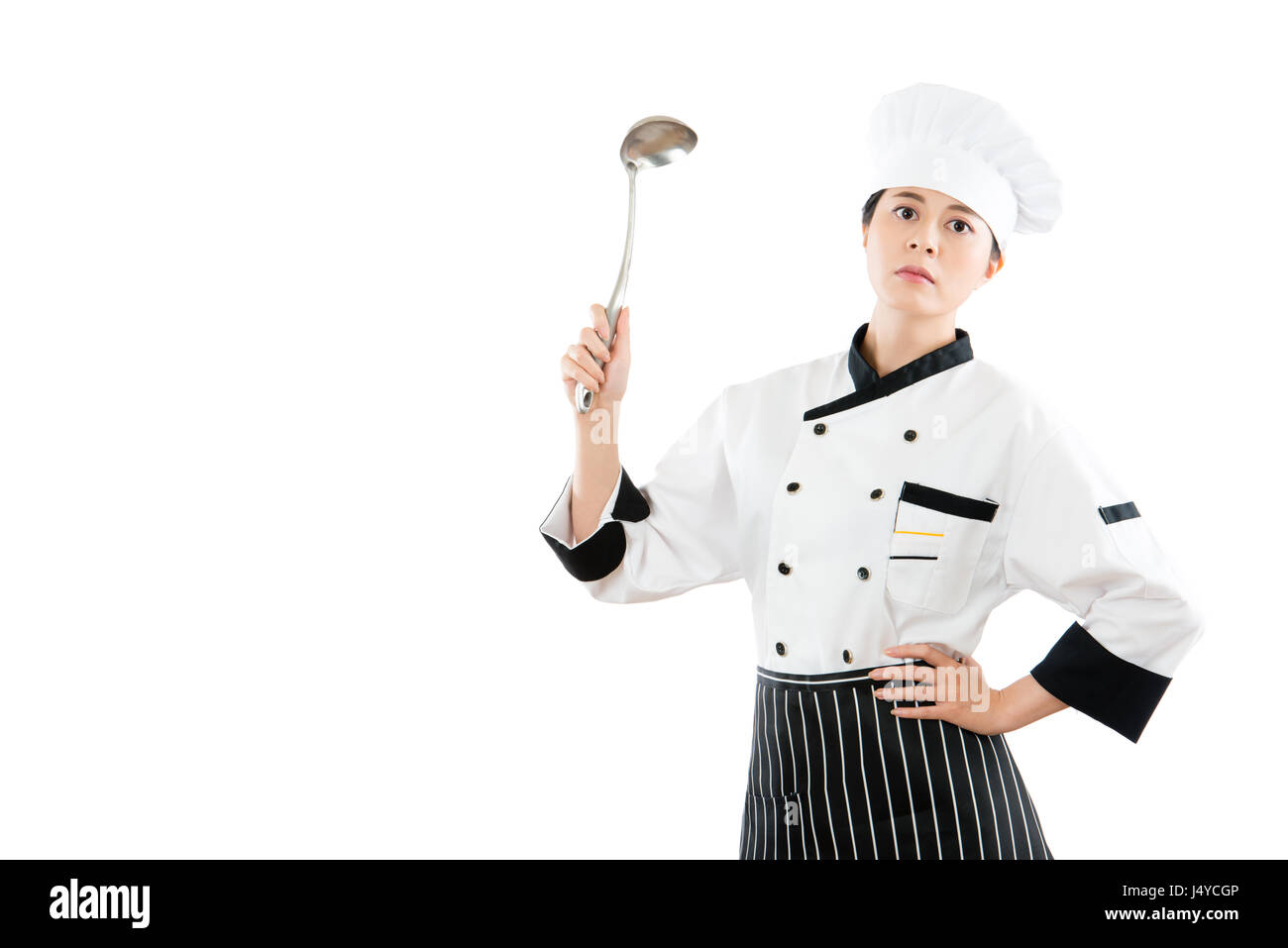 asian chinese woman chef holding a stainless steel spoon showing on a copyspace serious looking at the front of standing on white background with blan Stock Photo