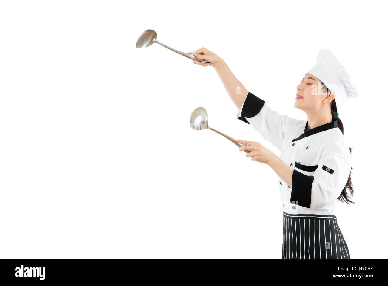 friendly chef in the copyspace on air using spatula and spoon tools cooking and enjoying the scent of food standing on the background of the white wal Stock Photo