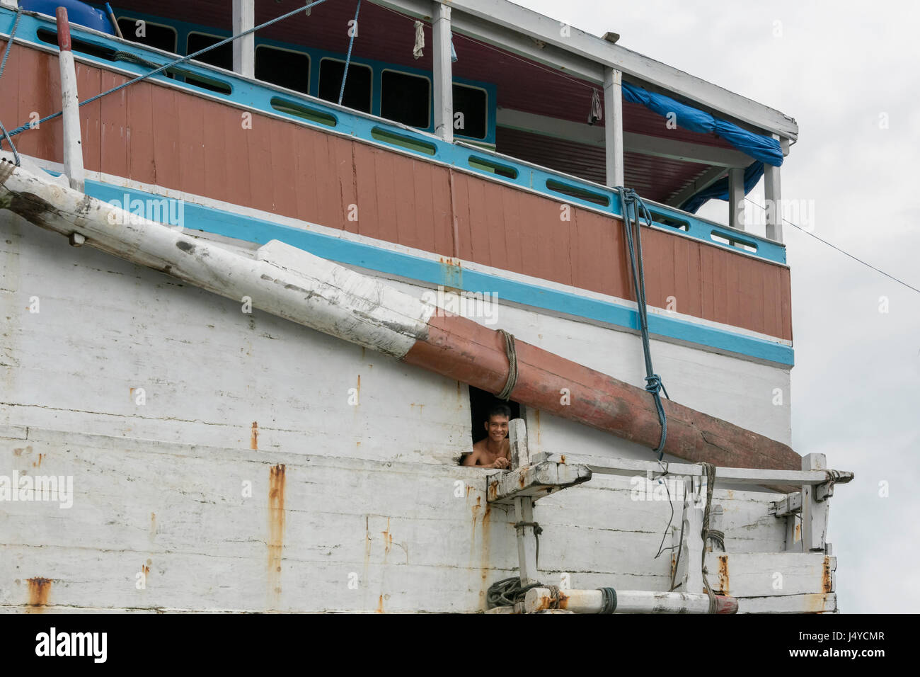 Crewman next to Bugis-Makassar steering oar on old caravel-design pinisi, Sunda Kelap Harbour, Jakarta, Indonesia Stock Photo