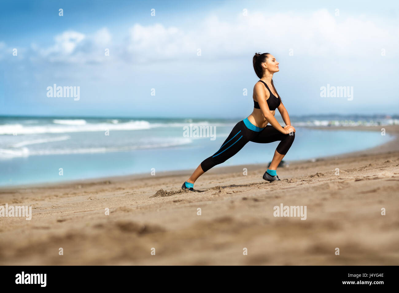 Attractive woman stretching on the beach, workout outdoor Stock Photo