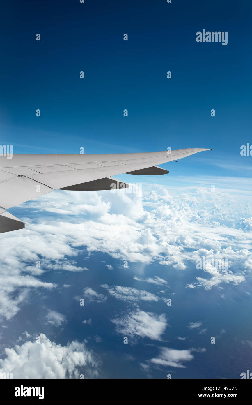 Wing of airplane flying above the clouds in the sky Stock Photo - Alamy