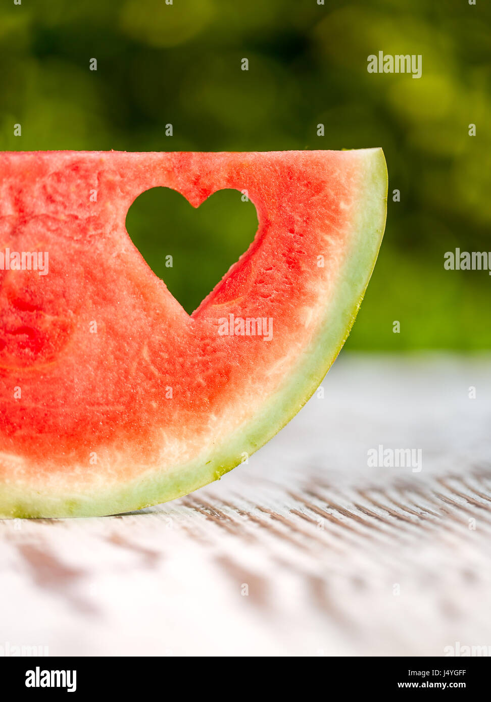 slice watermelon with a hole in the shape of heart on a wooden table Stock Photo
