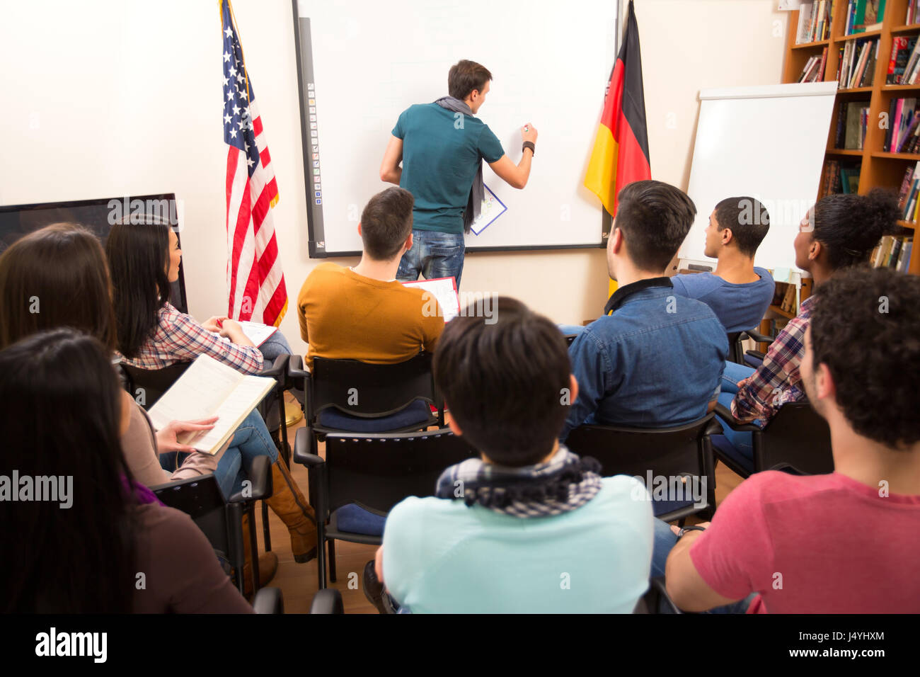 Handsome male lecturer drawing diagram in front of students on the blackboard Stock Photo
