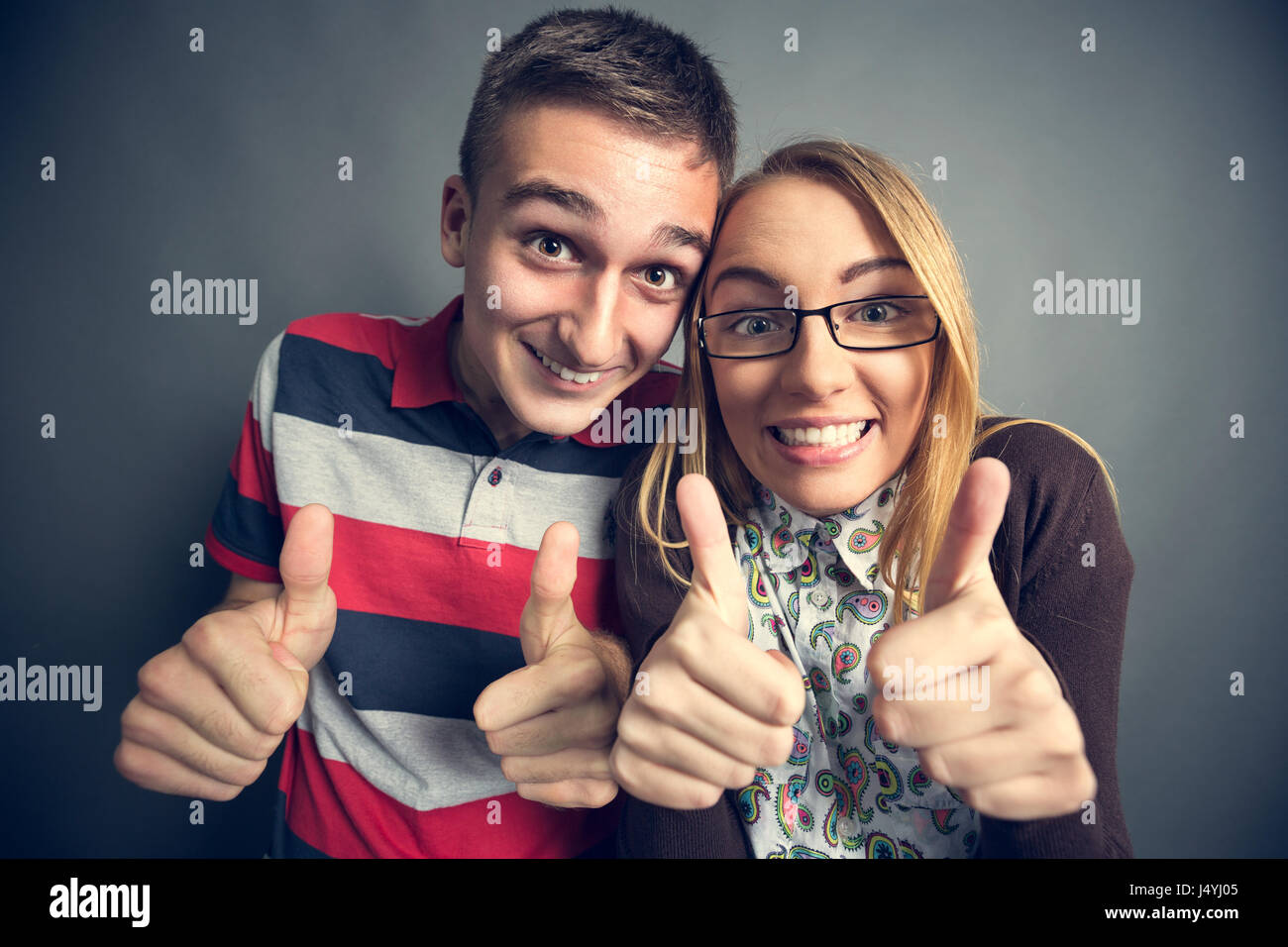 Happy nerdy couple showing thumbs up Stock Photo