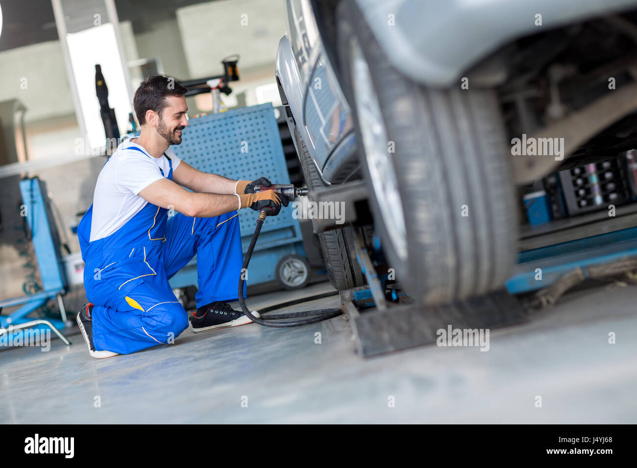 Car wheel change by mechanic with air wrench in Stock Photo