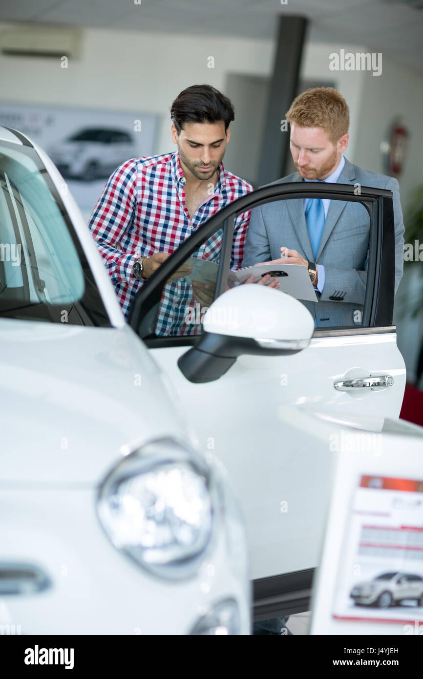Car agent showing vehicle male client at car dealership saloon Stock