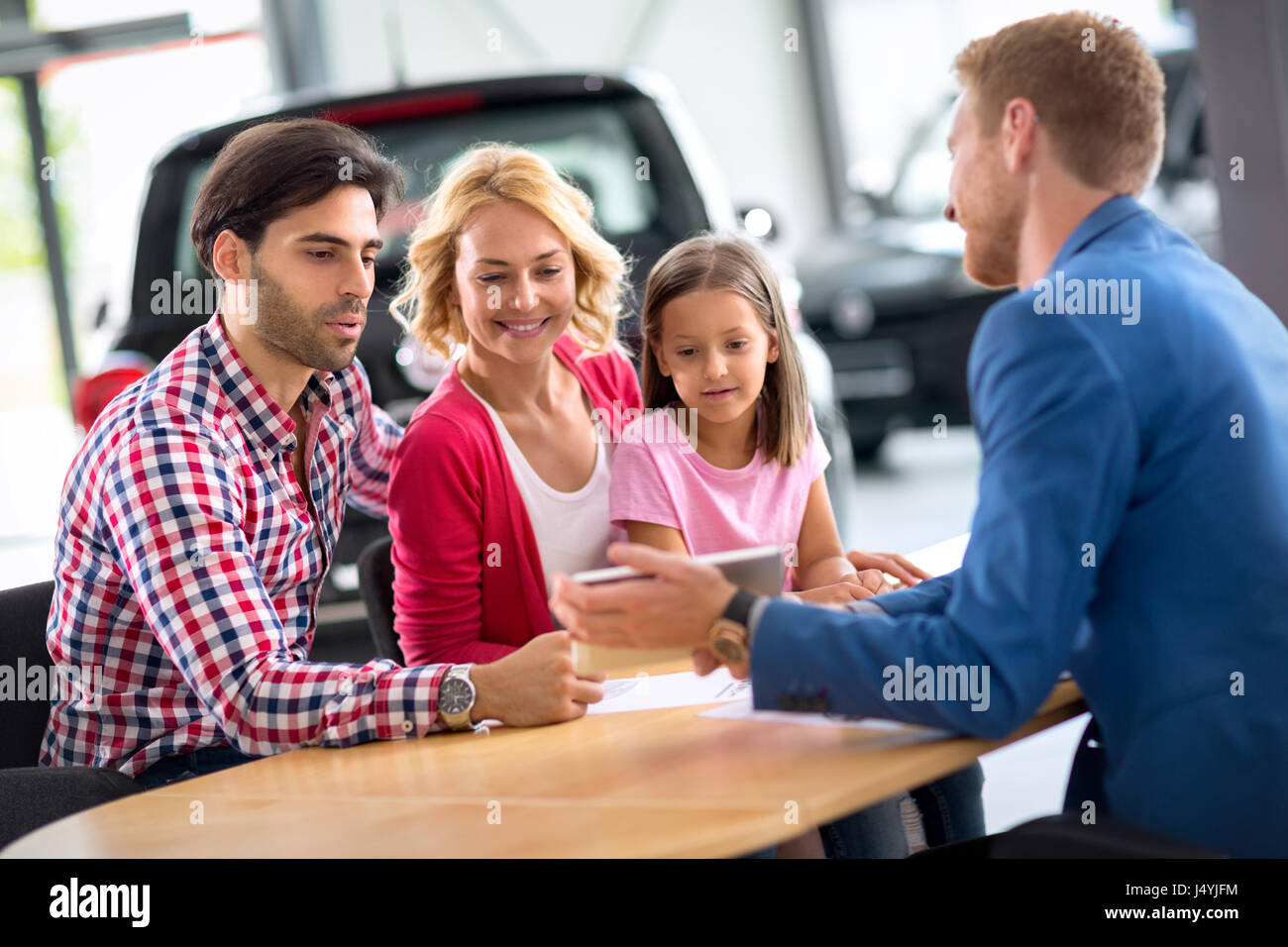 Smiling young family with car dealer, concept buy new car Stock Photo
