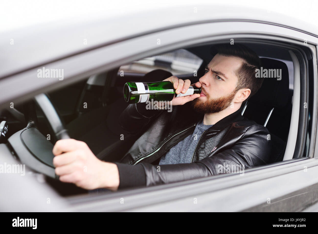 Drunk man with a bottle of beer driving a car Stock Photo - Alamy