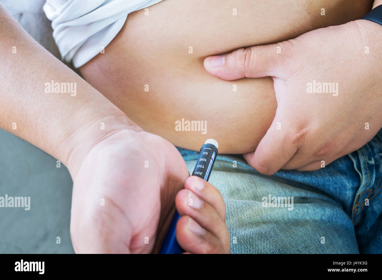 Male diabetes patient injecting insulin in his abdomen area Stock Photo