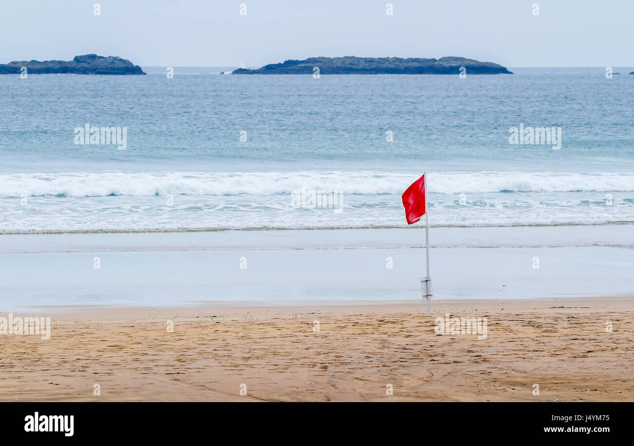 Red flag on the beech at Portrush, Northern Ireland indicating a hazard such as high surf or strong currents Stock Photo