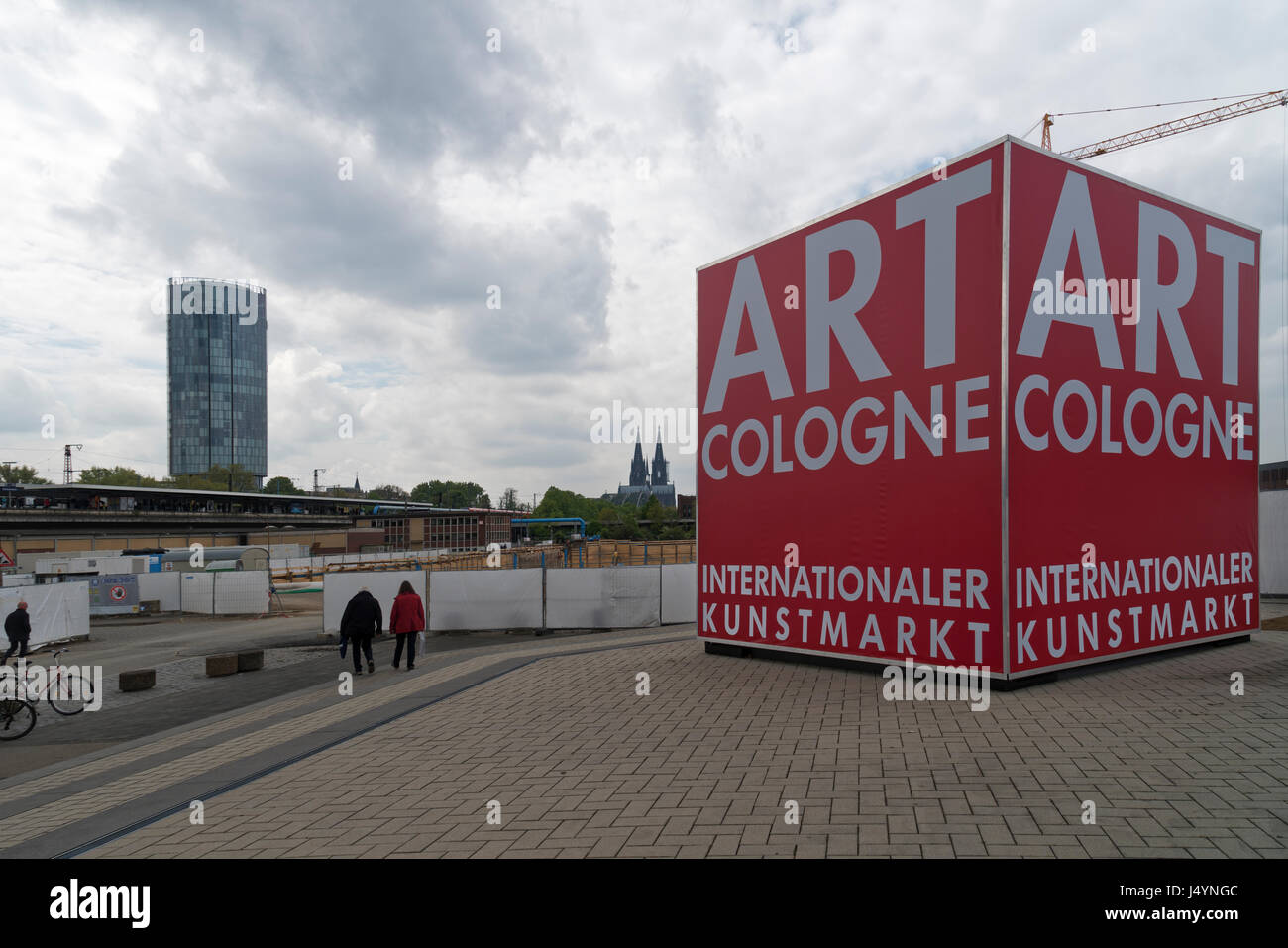 The red cube of Art Cologne in front of the skyline of Cologne, Germany with the Cathedral, Hohenzollernbridge and Koelntriangle skyscraper. Stock Photo