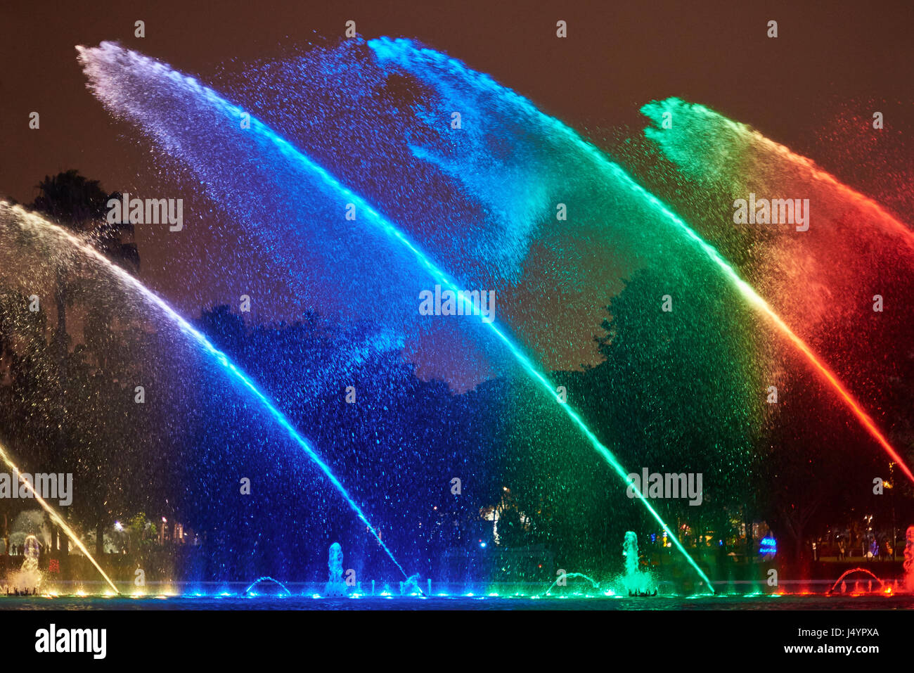 Rainbow color water in fountain at night Lima Peru. Colorful aqua show Stock Photo