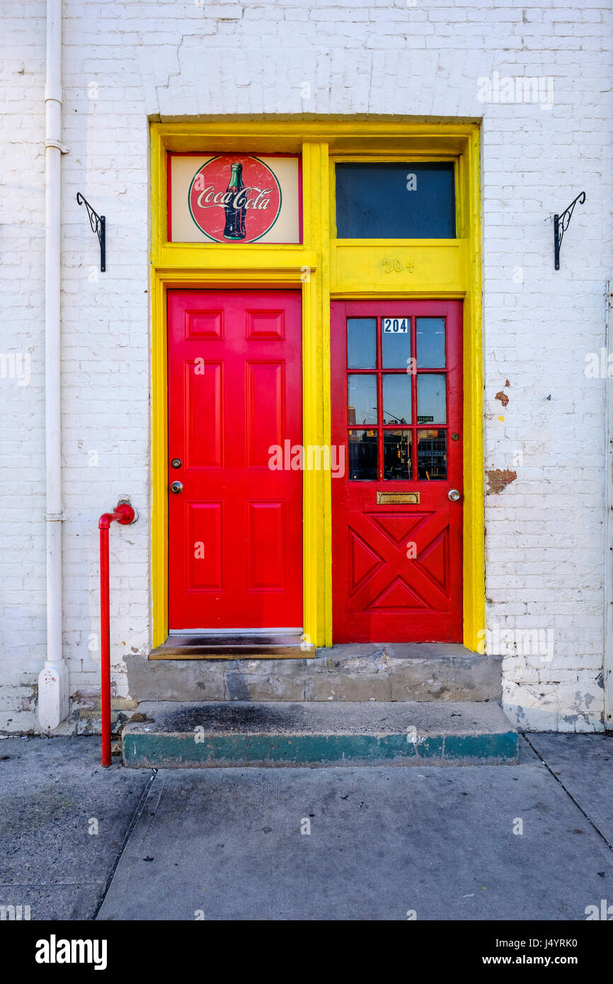 Two bright red doors side by side with yellow frames, and a classic Coca-Cola logo, colourful, colorful, door, London, Ontario, Canada. Stock Photo
