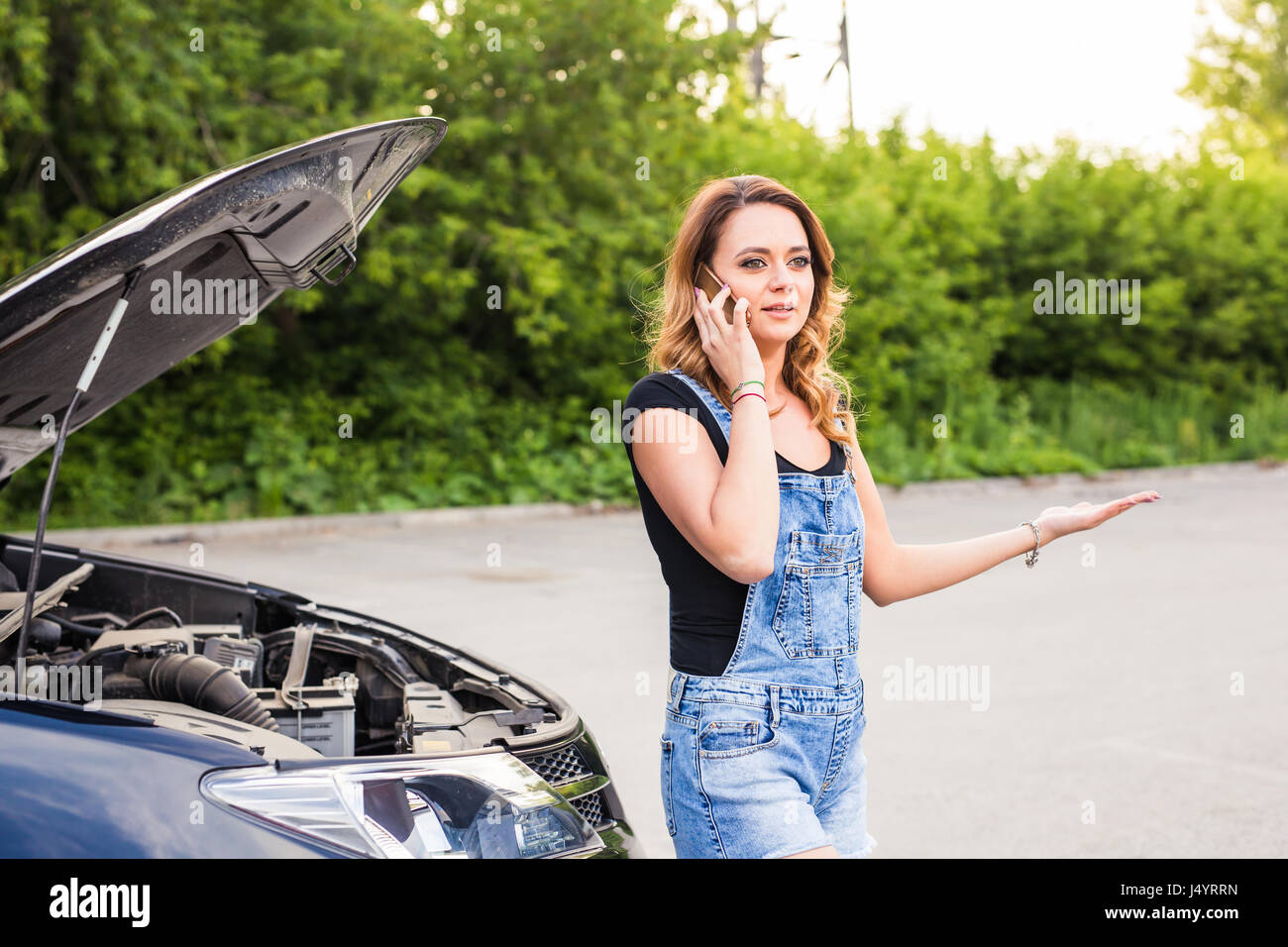 young woman with broken down car and hood open call for help Stock ...