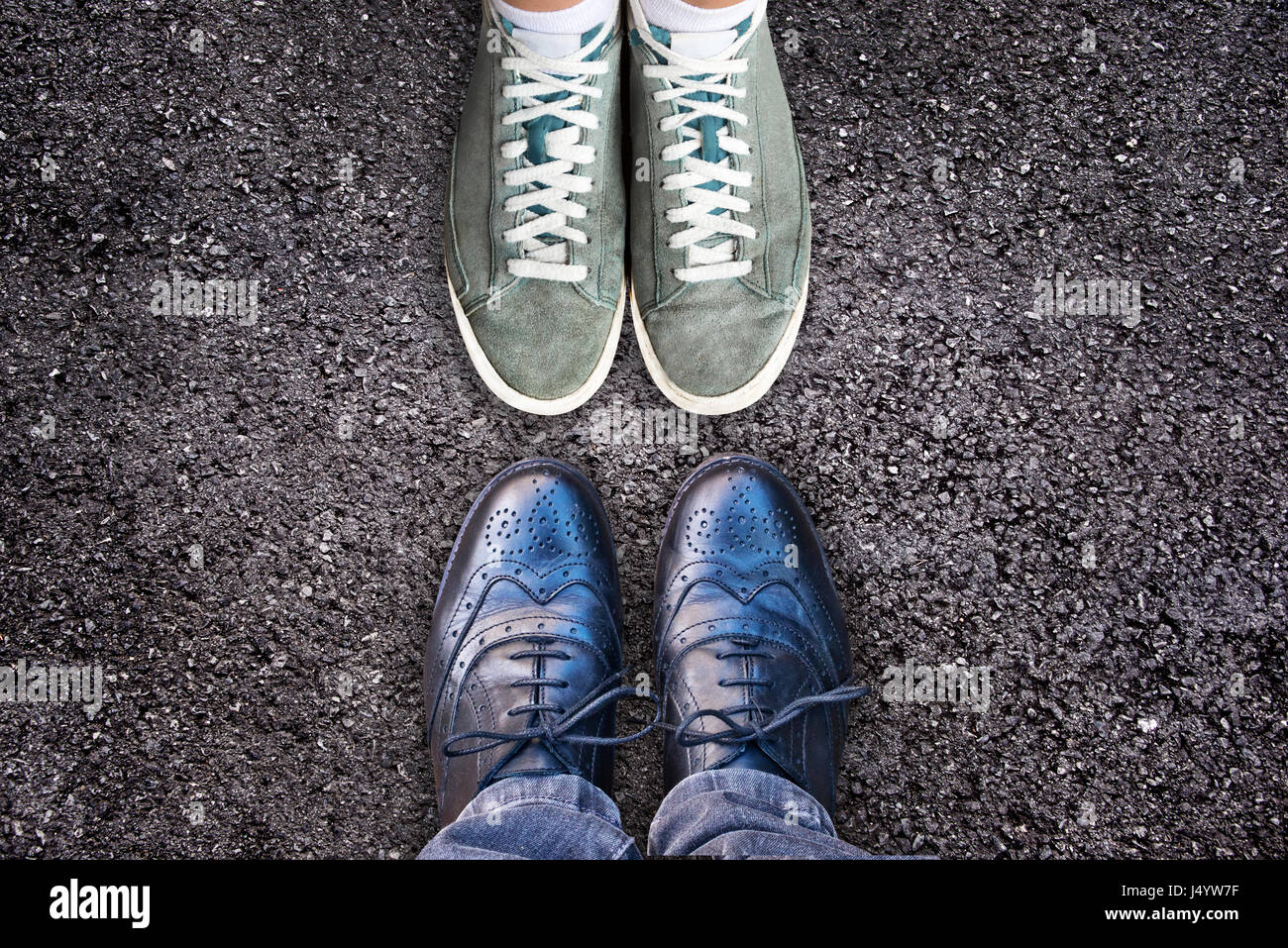 Sneakers and business shoes face to face on asphalt, work life balance concept Stock Photo