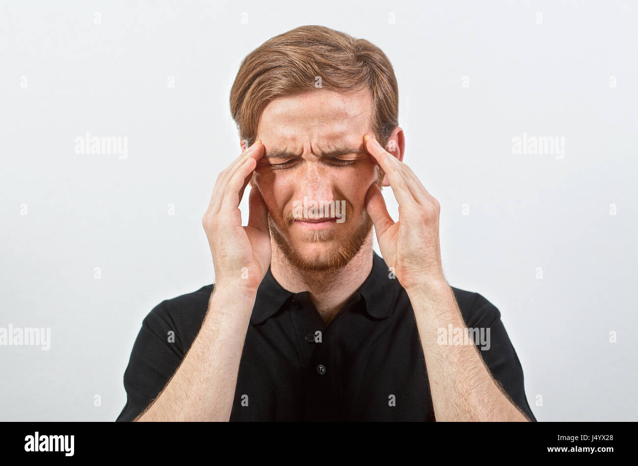 Headache. Unpleasant Young Adult Male in Black T-Shirt in Pain Touches His Head, Eyes Closed Stock Photo