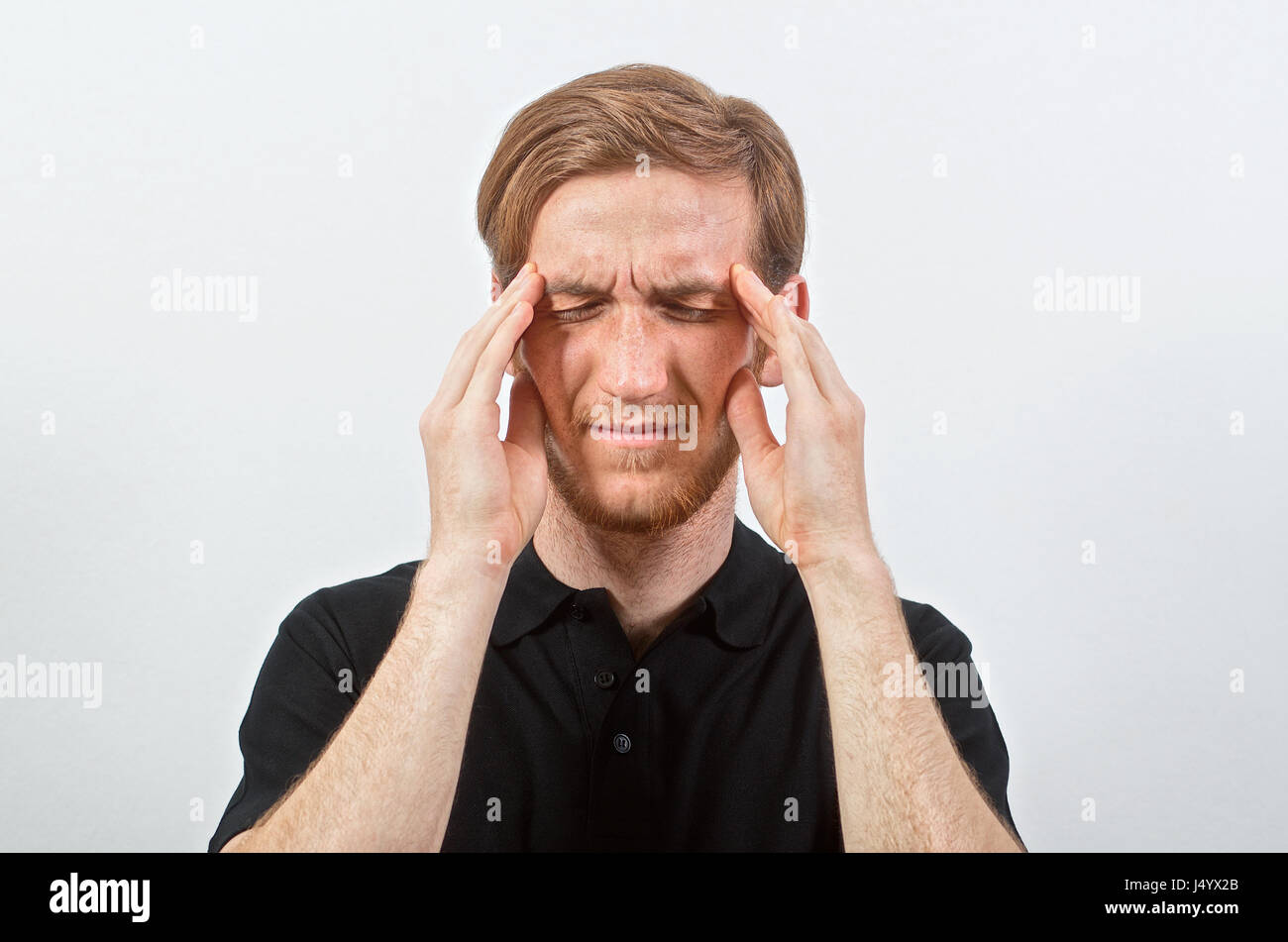 Headache. Unpleasant Young Adult Male in Black T-Shirt in Pain Touches His Head, Eyes Closed Stock Photo
