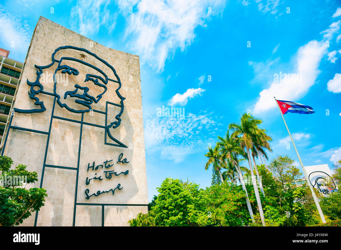 HAVANA - CIRCA JUNE, 2011: Cuban flag flies next to large scale portrait of the revolutionary Che Guevara at the Plaza de la Revolucion. Stock Photo