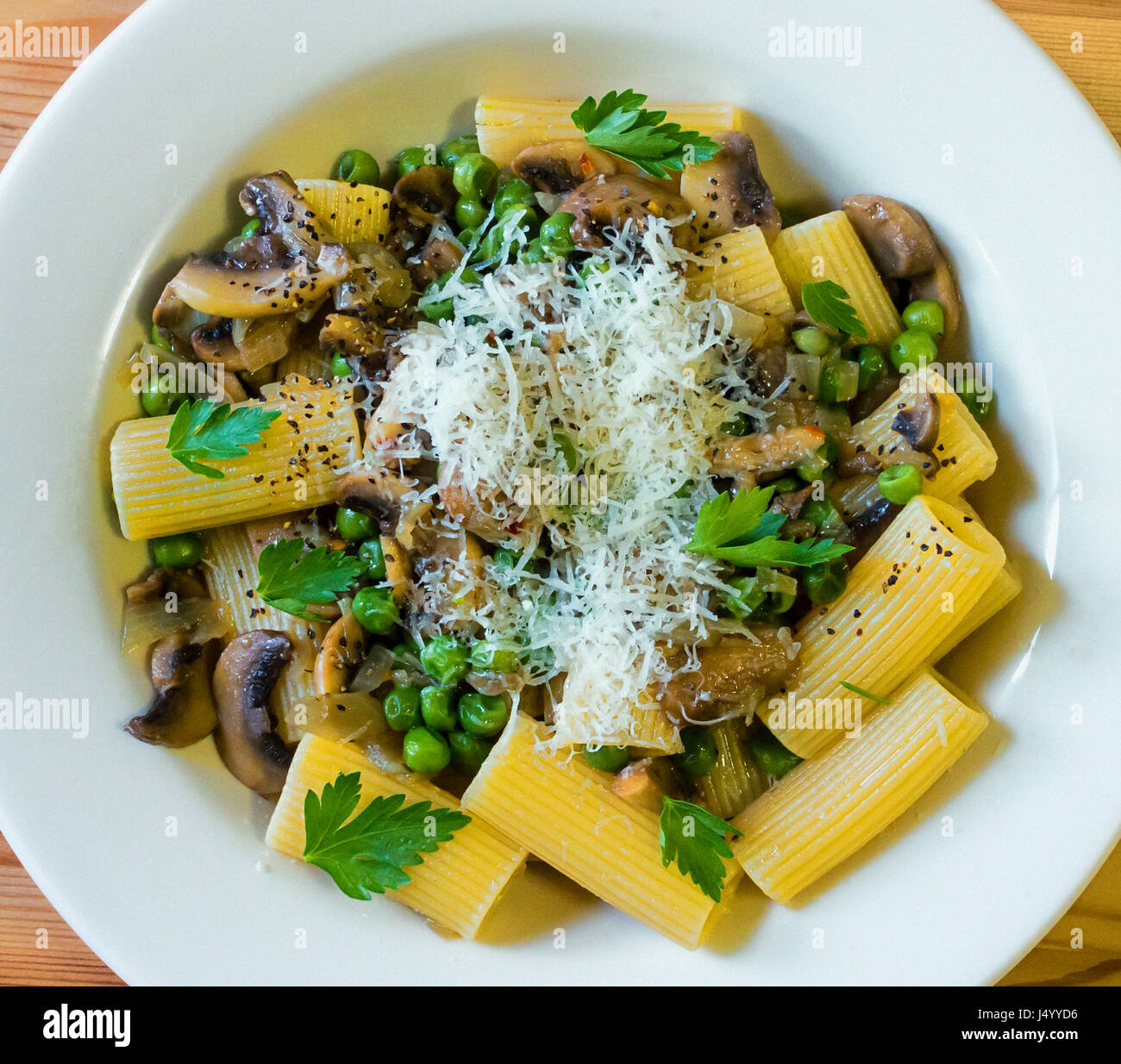 Rigatoni pasta with mushrooms, green peas, butter, and Parmigiano