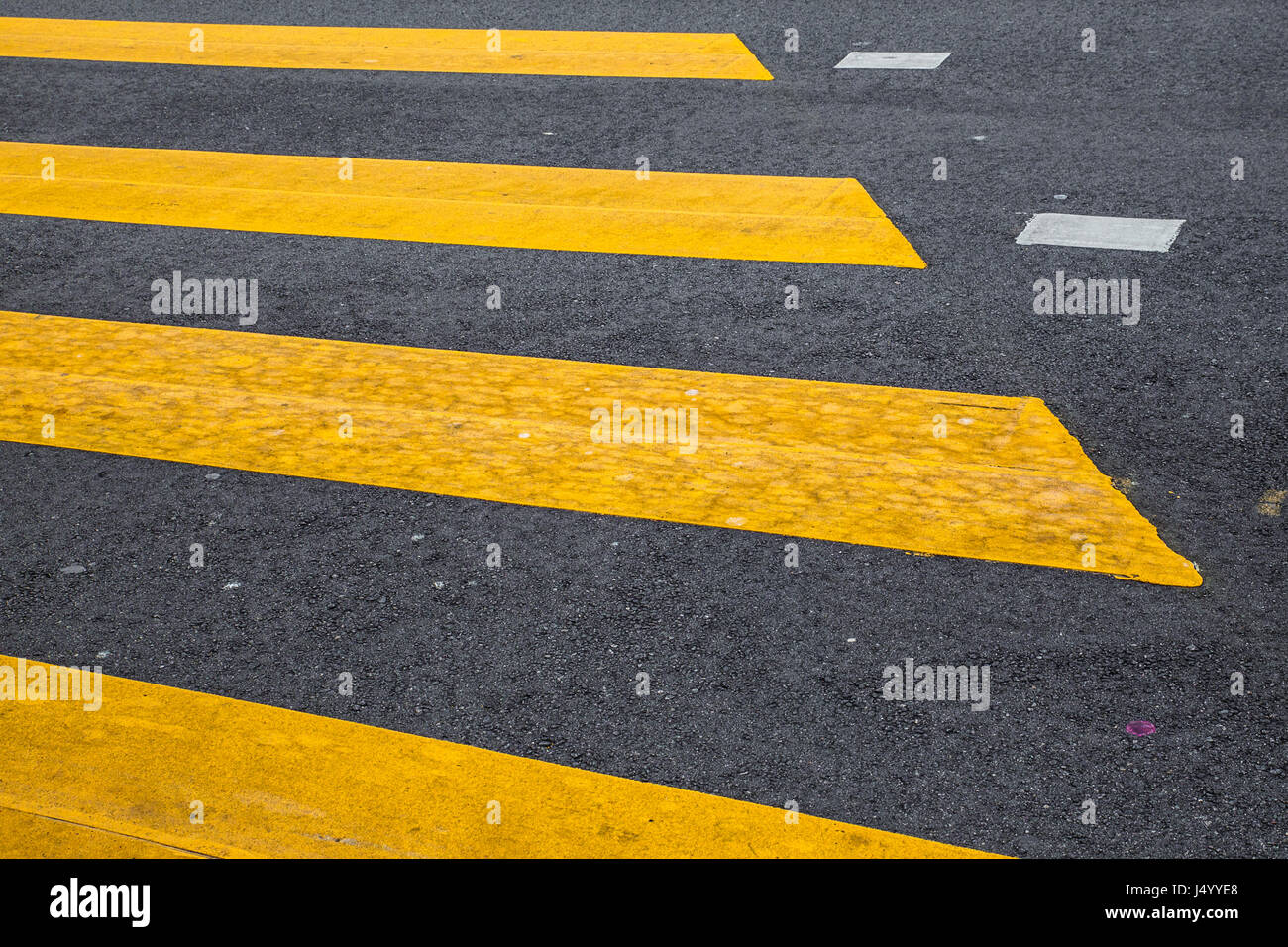Yellow painted crosswalk road line markings with moving car in background Stock Photo