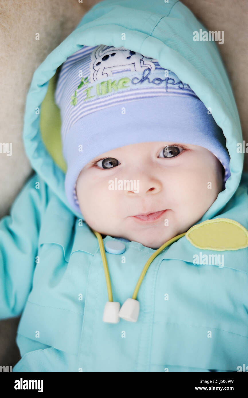 baby in blue jacket smiling at the camera Stock Photo
