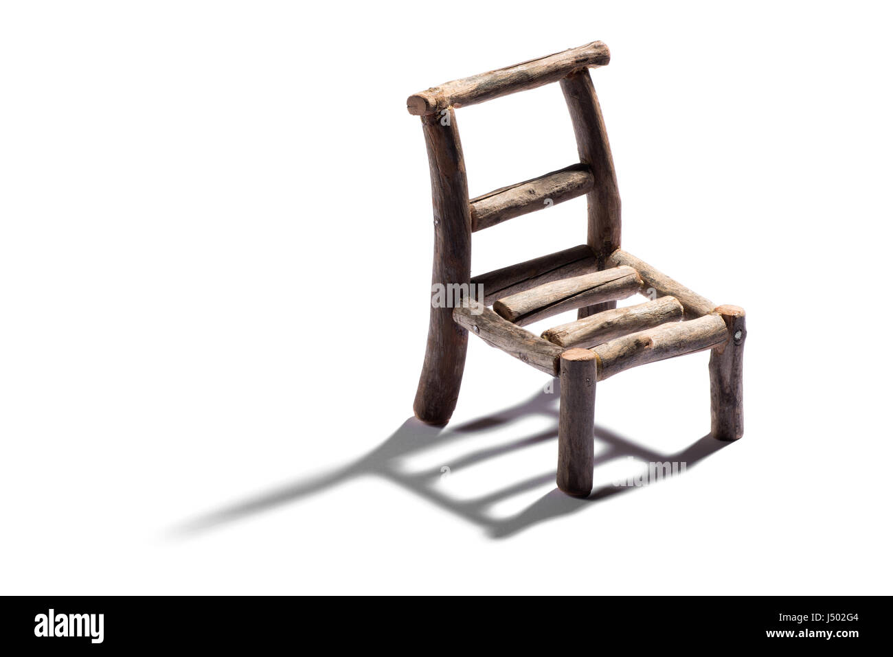 Small rustic handmade model of a chair made from rough wood casting a