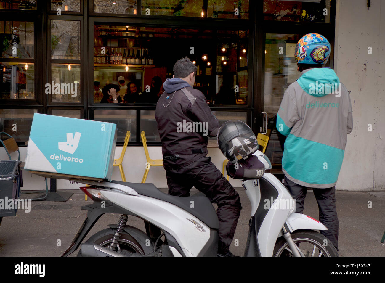 Deliveroo couriers waiting for food from a restaurant by Peckham Rye station in London,UK Stock Photo
